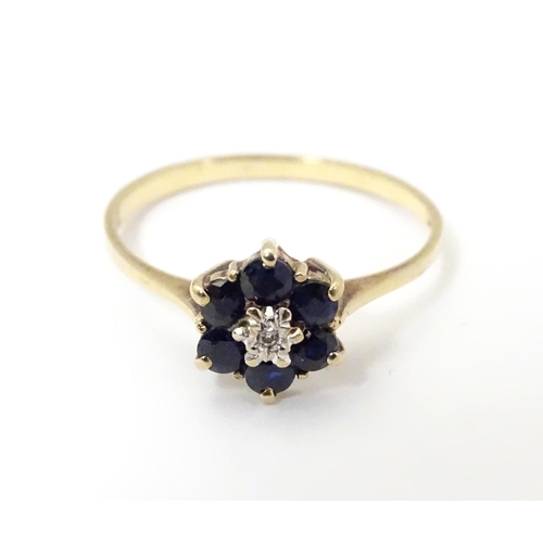 515 - A 9ct gold ring set with central diamond bordered by 6 sapphires in a cluster setting. Ring size app... 