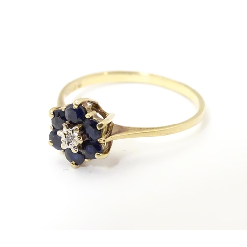 515 - A 9ct gold ring set with central diamond bordered by 6 sapphires in a cluster setting. Ring size app... 