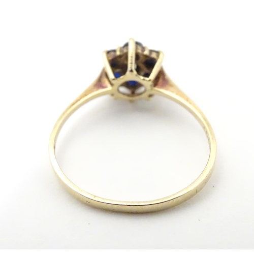 515 - A 9ct gold ring set with central diamond bordered by 6 sapphires in a cluster setting. Ring size app... 