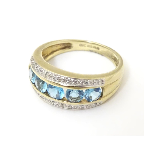 526 - A 9ct gold ring set with band of 5 topaz flanked bands of diamonds. Ring size approx M 1/2