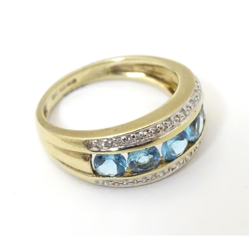 526 - A 9ct gold ring set with band of 5 topaz flanked bands of diamonds. Ring size approx M 1/2