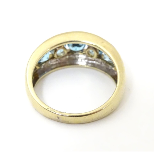 526 - A 9ct gold ring set with band of 5 topaz flanked bands of diamonds. Ring size approx M 1/2