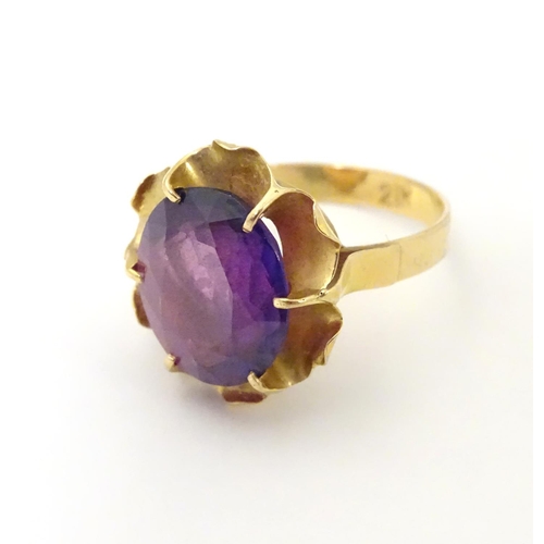 532 - A gold ring marked '21k' set with oval  facet cut purple coloured stone. Ring size approx K