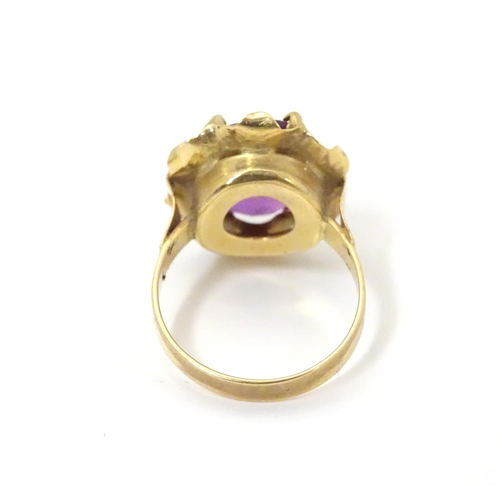 532 - A gold ring marked '21k' set with oval  facet cut purple coloured stone. Ring size approx K