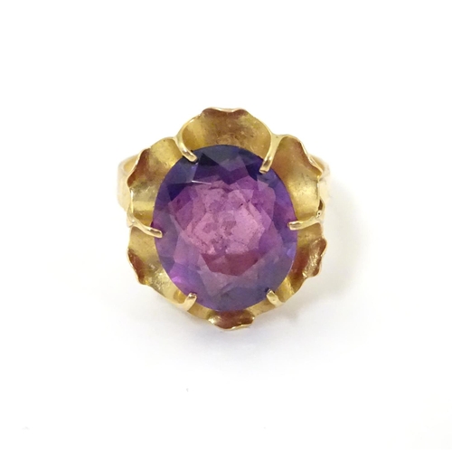 532 - A gold ring marked '21k' set with oval  facet cut purple coloured stone. Ring size approx K