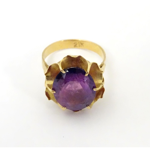 532 - A gold ring marked '21k' set with oval  facet cut purple coloured stone. Ring size approx K