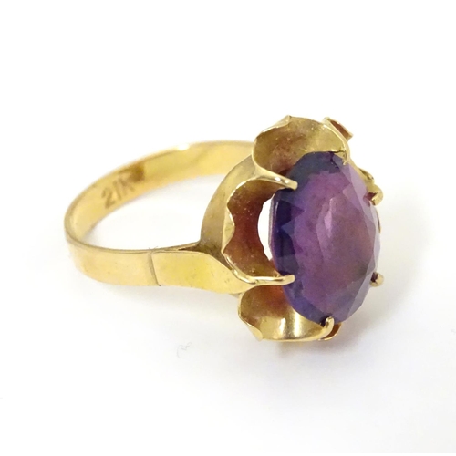 532 - A gold ring marked '21k' set with oval  facet cut purple coloured stone. Ring size approx K