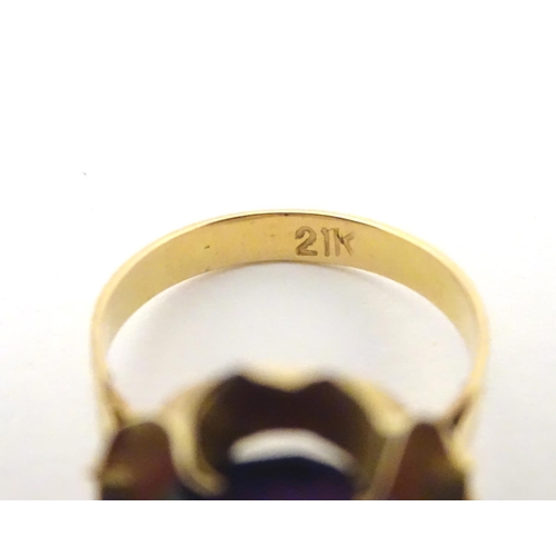 532 - A gold ring marked '21k' set with oval  facet cut purple coloured stone. Ring size approx K