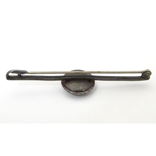 563 - A white metal bar brooch, stamped STERLING BERMUDA, the central circular section containing a white ... 