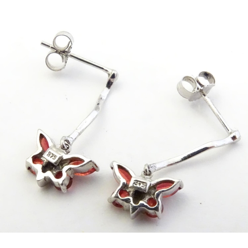 583 - 9ct white gold drop earrings with butterfly detail red stones. 3/4