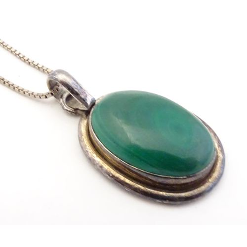 586 - A silver pedant and chain the pendant set with malachite coloured cabochon. The pendant 1 3/4