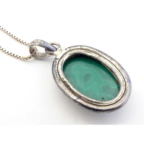 586 - A silver pedant and chain the pendant set with malachite coloured cabochon. The pendant 1 3/4