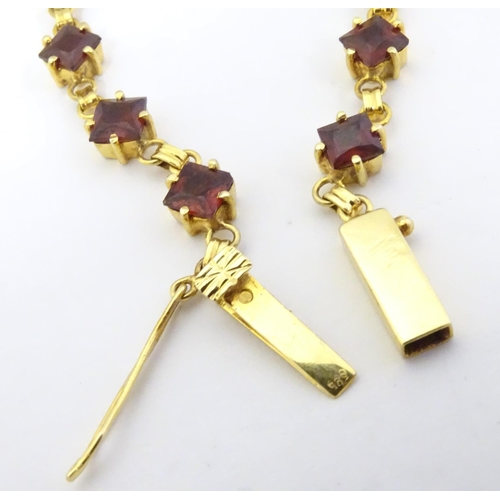 587 - A 14ct gold bracelet set with 14 garnets together with matching stud earrings