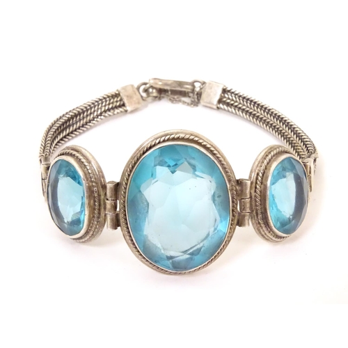 598 - A white metal bracelet set with three large graduated aquamarine coloured stones.