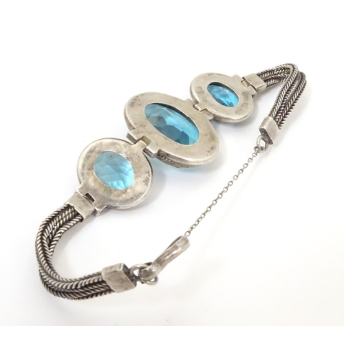 598 - A white metal bracelet set with three large graduated aquamarine coloured stones.