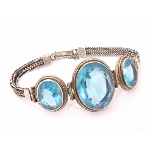 598 - A white metal bracelet set with three large graduated aquamarine coloured stones.