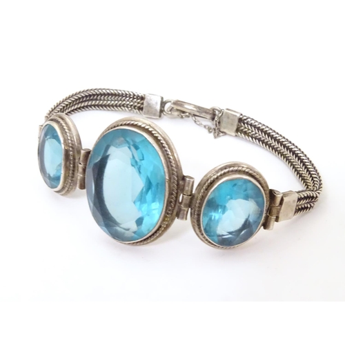 598 - A white metal bracelet set with three large graduated aquamarine coloured stones.