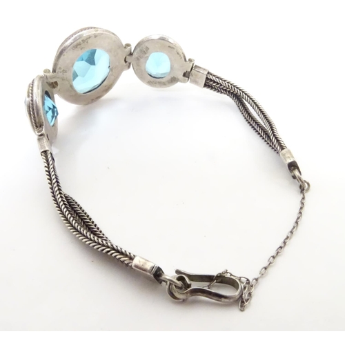 598 - A white metal bracelet set with three large graduated aquamarine coloured stones.