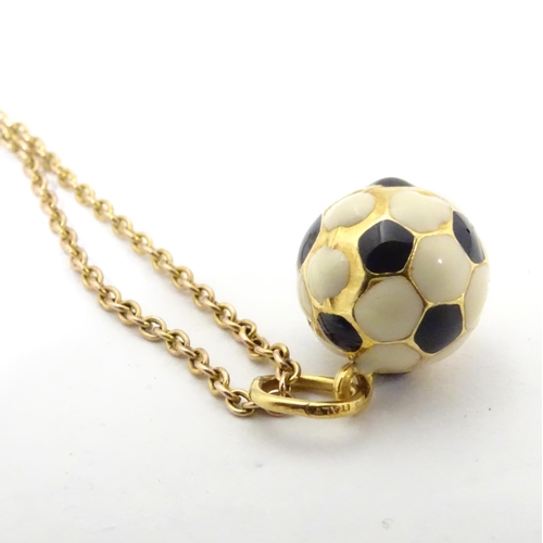 603 - A novelty pendant / charm formed as a football with enamel decoration. on a 9ct gold chain Approx 16... 