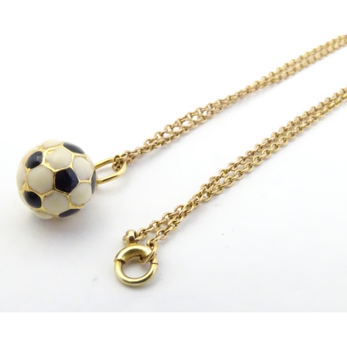 603 - A novelty pendant / charm formed as a football with enamel decoration. on a 9ct gold chain Approx 16... 