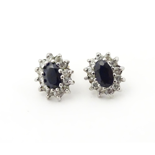 619 - A pair of 9ct gold stud earrings set with central sapphire coloured spinel bordered by white stones.... 