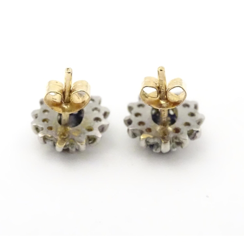 619 - A pair of 9ct gold stud earrings set with central sapphire coloured spinel bordered by white stones.... 