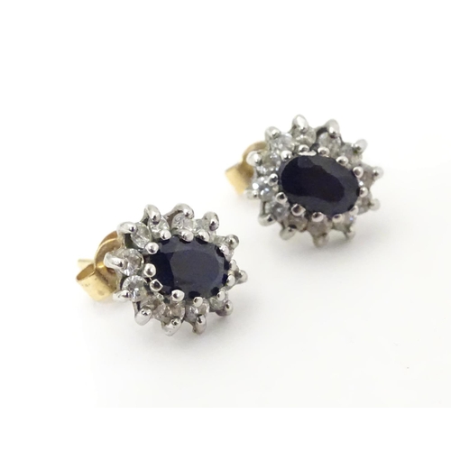 619 - A pair of 9ct gold stud earrings set with central sapphire coloured spinel bordered by white stones.... 