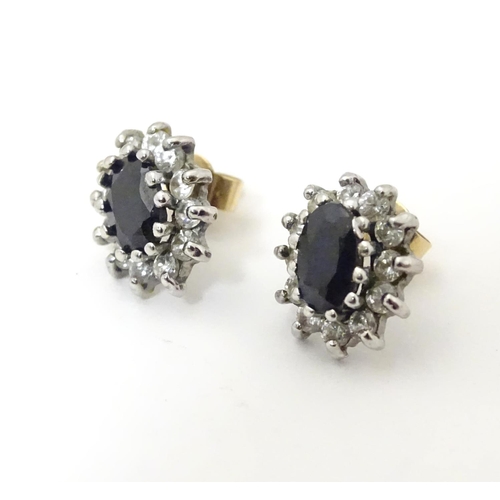 619 - A pair of 9ct gold stud earrings set with central sapphire coloured spinel bordered by white stones.... 