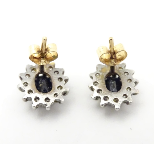 619 - A pair of 9ct gold stud earrings set with central sapphire coloured spinel bordered by white stones.... 