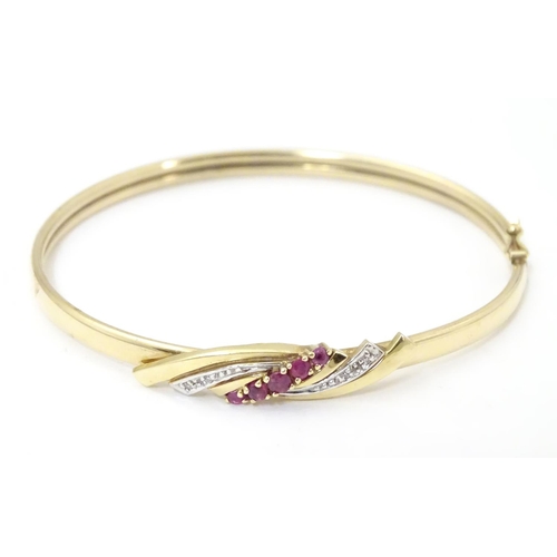 624 - A 9ct gold bracelet of bangle form set with rubies and diamonds