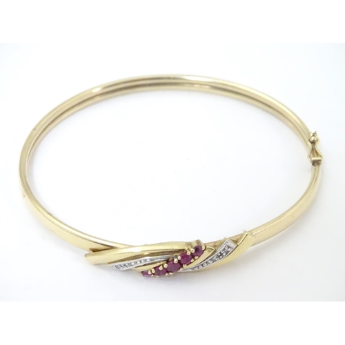 624 - A 9ct gold bracelet of bangle form set with rubies and diamonds