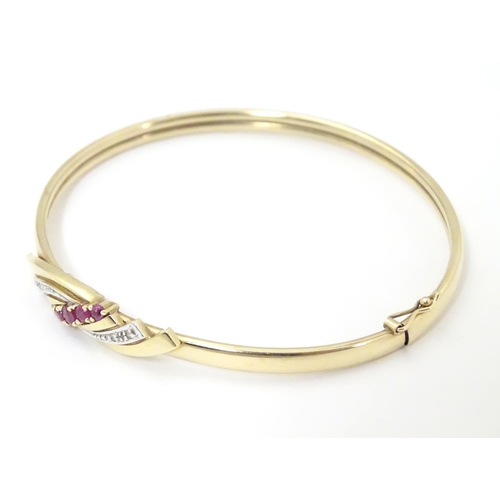 624 - A 9ct gold bracelet of bangle form set with rubies and diamonds