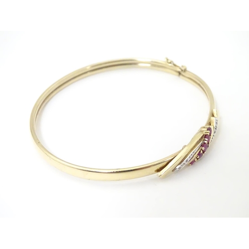 624 - A 9ct gold bracelet of bangle form set with rubies and diamonds