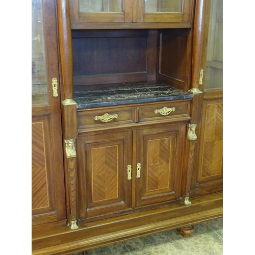 1384 - A large continental mahogany cabinet with a moulded cornice above gilt metal mounts and glazed doors... 