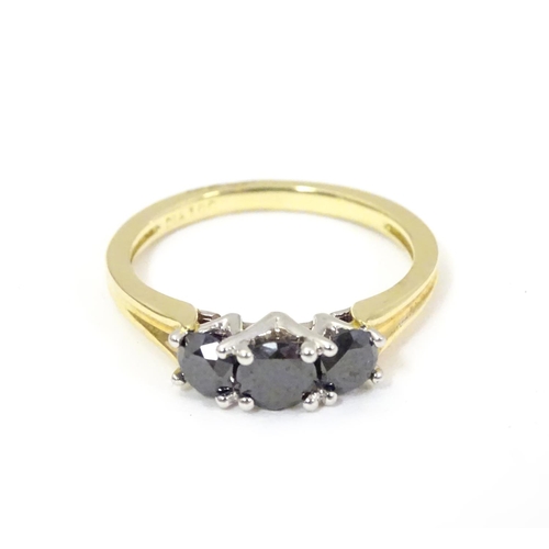 534 - An 18ct gold ring set with trio of black diamonds. Ring size approx O