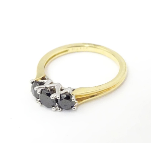 534 - An 18ct gold ring set with trio of black diamonds. Ring size approx O