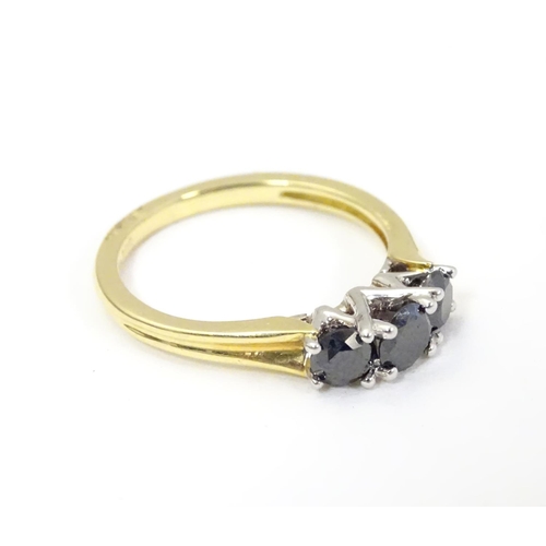 534 - An 18ct gold ring set with trio of black diamonds. Ring size approx O