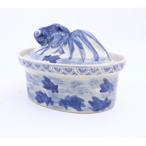 13 - A Chinese blue and white dish and cover of oval form, the lid surmounted by a fish in relief, the bo... 