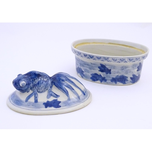 13 - A Chinese blue and white dish and cover of oval form, the lid surmounted by a fish in relief, the bo... 