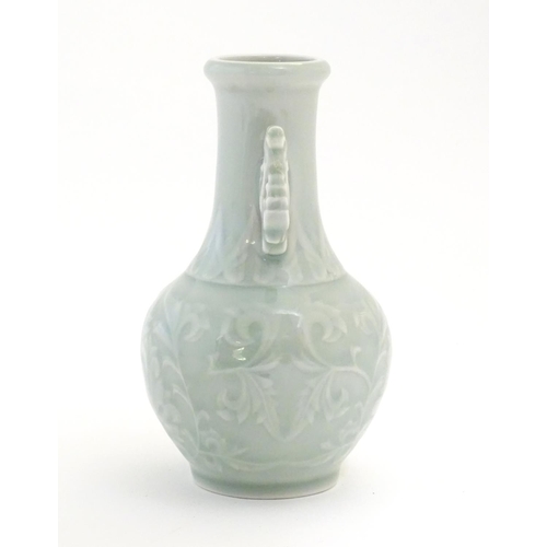 30 - A Chinese celadon green baluster vase with twin handles and stylised foliate design. Approx. 6 1/4