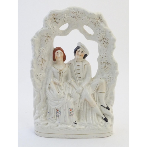50 - A Staffordshire pottery flat back figural group depicting a seated young couple under a garden arch.... 
