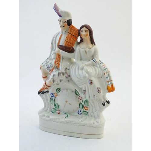 63 - A Staffordshire flat back figural group depicting a Scottish highland couple with clock detail below... 