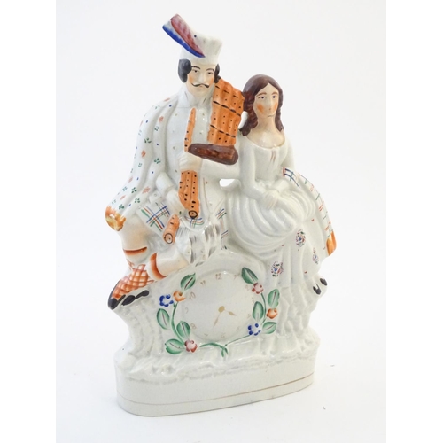 63 - A Staffordshire flat back figural group depicting a Scottish highland couple with clock detail below... 