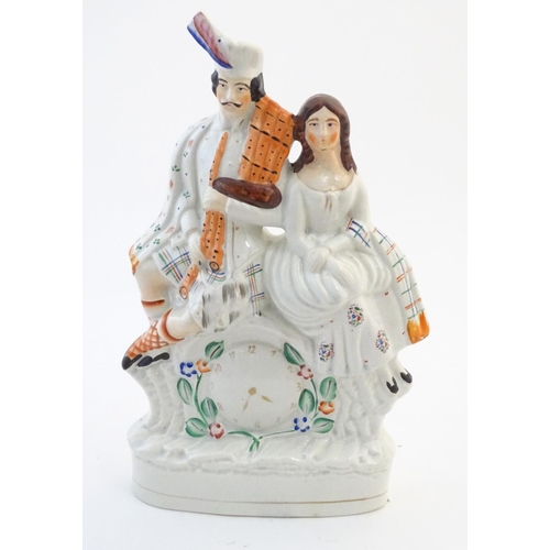 63 - A Staffordshire flat back figural group depicting a Scottish highland couple with clock detail below... 