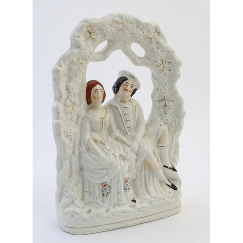 69 - A Staffordshire pottery flat back figural group depicting a seated young couple under a garden arch.... 