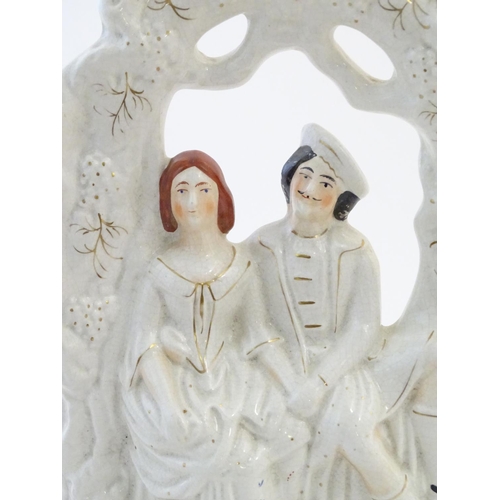 69 - A Staffordshire pottery flat back figural group depicting a seated young couple under a garden arch.... 