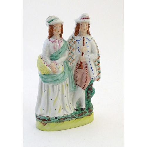 73 - A Staffordshire pottery figural group depicting two figures, one with a basket of flowers, the other... 