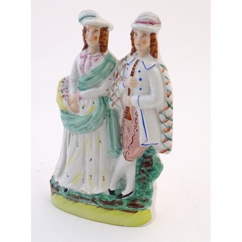 73 - A Staffordshire pottery figural group depicting two figures, one with a basket of flowers, the other... 