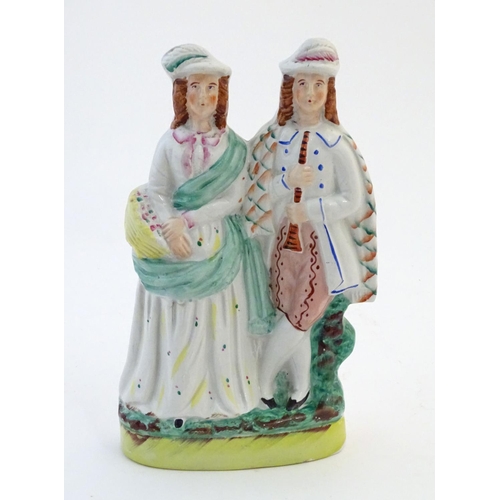 73 - A Staffordshire pottery figural group depicting two figures, one with a basket of flowers, the other... 