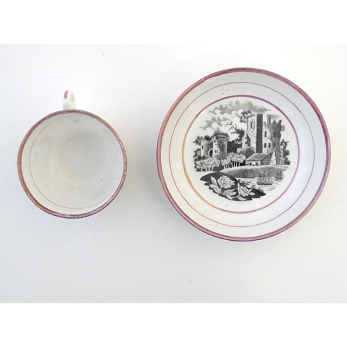 118 - A tea cup and saucer with monochrome transfer decoration depicting a river landscape with a ship and... 